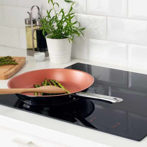 Close-up of copper-colored IKEA OUMBÄRLIG Frying Pan, 28 cm (11") on stove