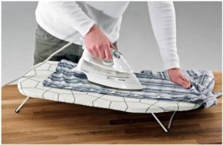 Person ironing clothes on the IKEA Ironing Board Table, showing ample surface area and sturdy construction 40242889