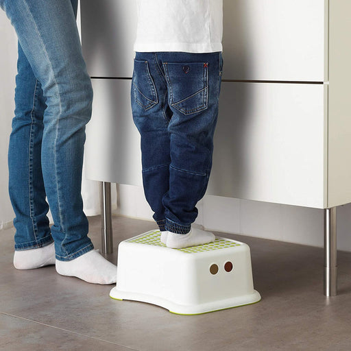 A child standing on the IKEA children's stool reaches a high shelf, demonstrating its safe and reliable design.  40248419